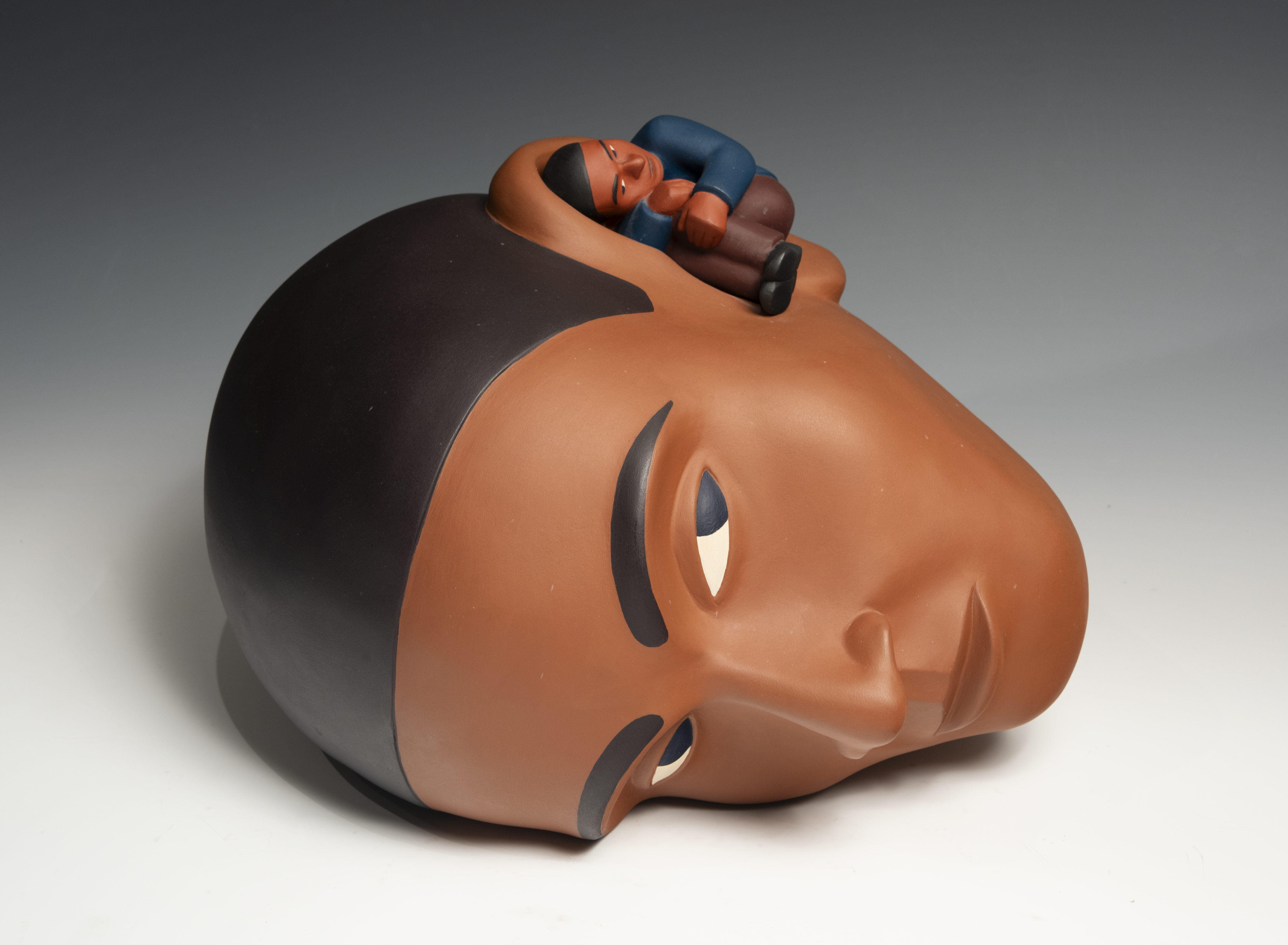 Tom Nussbaum sculpture of a man with his ear to the ground and a smaller man inside of his other ear
