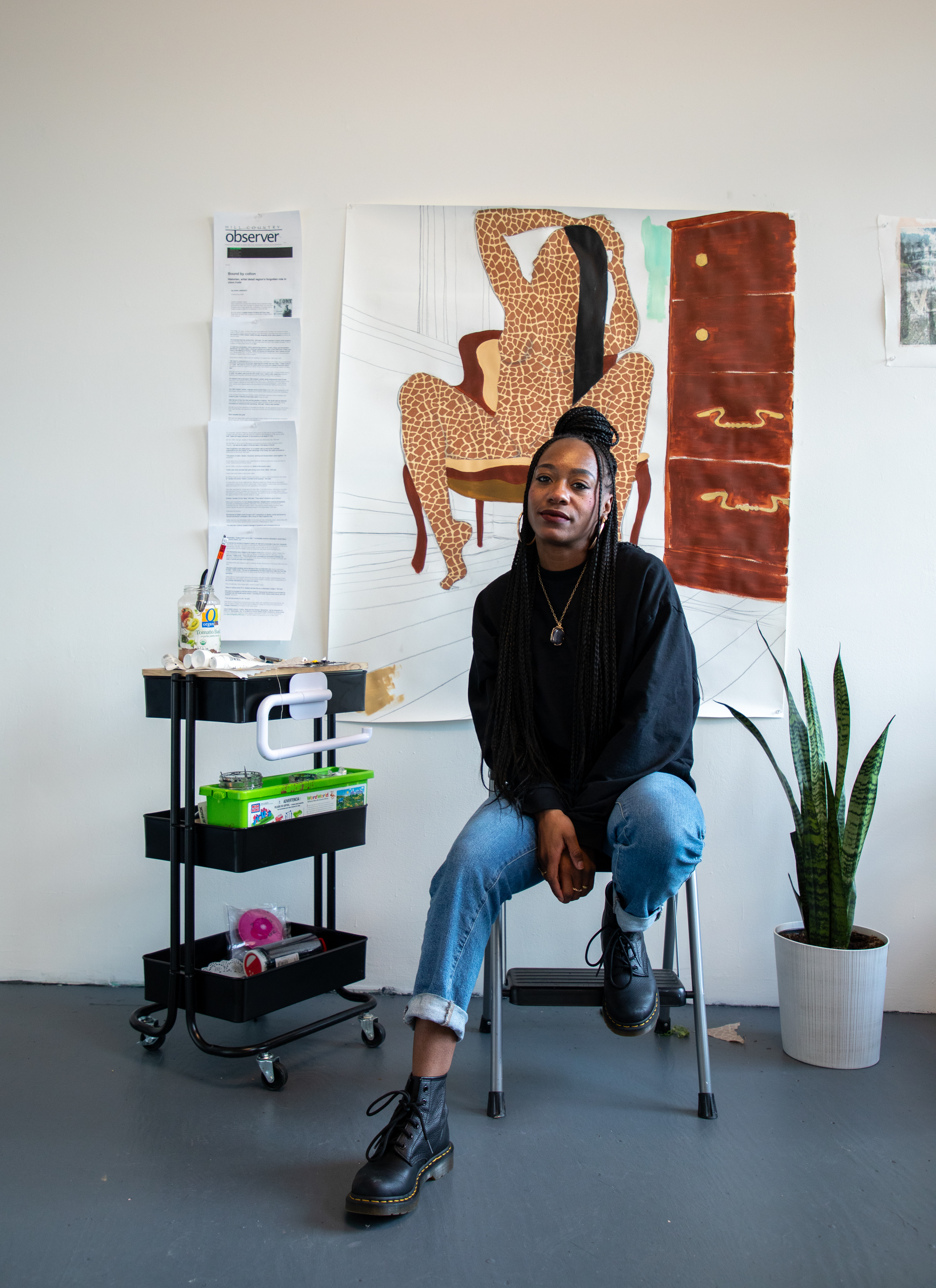 Jazlyne Sabree sitting in front of her artwork