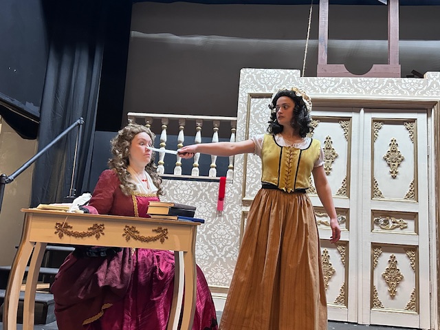 Actors rehearsing the revolutionists on stage, one holding a knife in the other's face