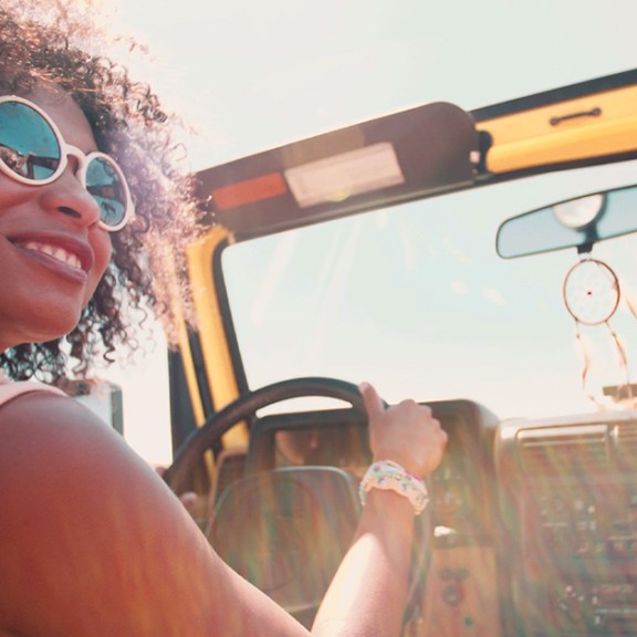 Woman sitting in a convertible car with sunglasses on