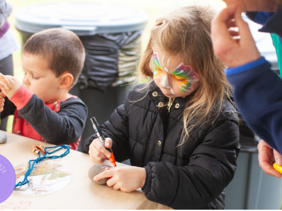 child doing arts and crafts with face paint on