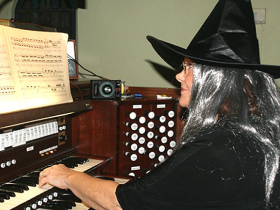 A woman dressed as a witch playing the piano