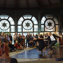 Two dancers holding hands while one leans back in front of an audience inside the historic Asbury Park Carousel Building