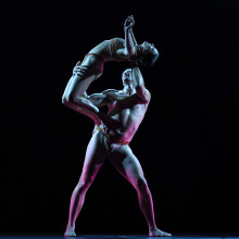 Two dancers on stage in a physically acrobatic balance shape.