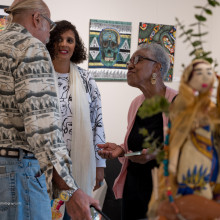 3 people are having a discussion in front of 2 and 3 dimensional art work