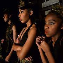 performers in costume look onstage from the wings during a performance