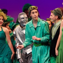 an action shot of kids in all green costumes performing a production of The Lorax