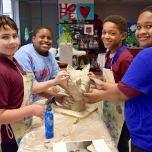 A group of kids happily work on a sculpture together