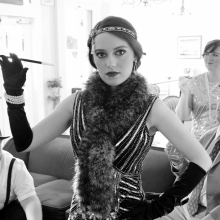 A black and white photo of group dressed in vintage 20s clothing cosplaying flappers as a speakeasy