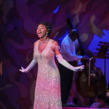 A woman in a sparkling golden vintage dress singing on stage
