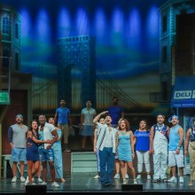 a group of people standing onstage performing In the Heights