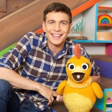 a young man in blue jeans and a plaid shirt holding a toy duck sitting on steps