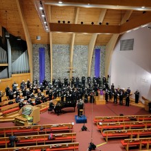 A choir performing in a church with wooden pews