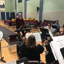 a group of musicians with sheet music in front of them rehearsing