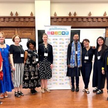 a group of fancy dressed Arts Horizons employees pose in front of a company banner