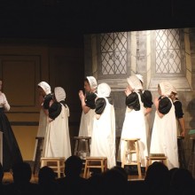 a scene from Pride and Prejudice with children in class with their teacher in their period piece school costumes