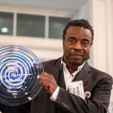 Revered local artist Willie Cole with a glass award made by GlassRoots studio artists