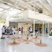People walking around an exhibition in the Domestic Arts Building. At the center of the photo is a sprawling cactus sculptur