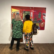 A pair of women in Hunterdon Art Museum admiring the painting Red Night by Sarah McEneaney