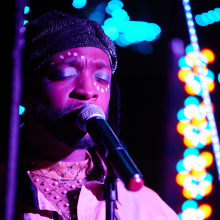 A man wearing face paint is singing into a microphone