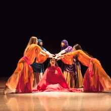 A group of dancers wearing flowy matching costumes on a stage