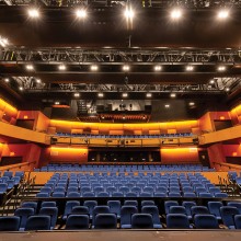 Rows of empty blue chairs in a large auditorium of the New Brunswick Performing Arts Center