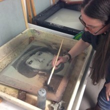 a woman in glasses working on a screenprint of a woman in a military uniform