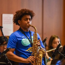 A boy playing the saxophone in front of a music class