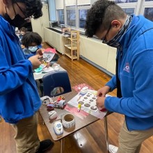 two preteens are using hole puncher stencils to make art