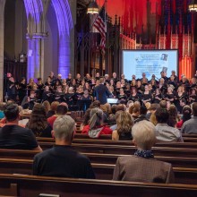 A choir performs in front of a projector screen in a church