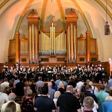 A large group of people standing in a church performing in a choir