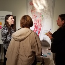 Three women standing in front of a poster at a professional development event