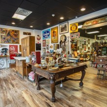 A room in Gallery On Main filled with antique furniture, trinkets, art, and signs