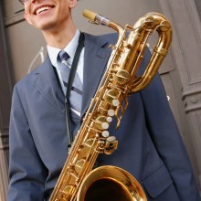 a man in a suit smiling with his saxophone