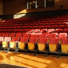 rows of empty red theatre seats on a performance space