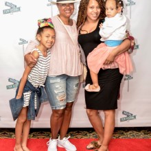 Two adults and two children posing for a photo on a red carpet