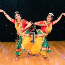 Two young dancers smiling while standing in an intricate pose before performance