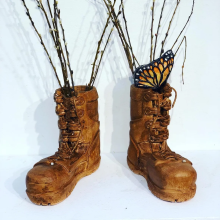 a pair of clay military boots with a clay Monarch butterfly sitting on them