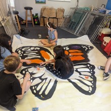 A group of children working together to paint a large butterfly