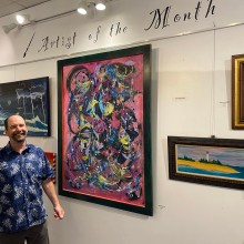 a man taking a photo in front of abstract paintings and paintings of lighthouses