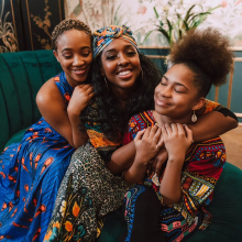 A group of three young Black women embracing each other