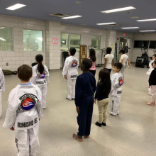 children stand in attention during a karate class, some in plainclothes and some in robes