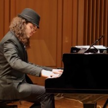 a man in a hat sitting at a piano