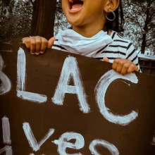 a little girl chanting while holding a Black Lives Matter sign