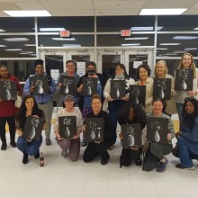 A group photo of people posing with their own variation of the same painting