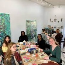 friends sitting around a table with art supplies and works in progress