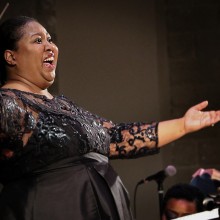Woman in a black sequined dress conducts the Choral Society