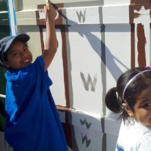 two young girls painting a wall and smiling