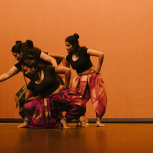 a group of women dancing together onstage in front of a red backdrop