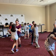 Kids in an education program practicing stage combat in a room with a pink carpet
